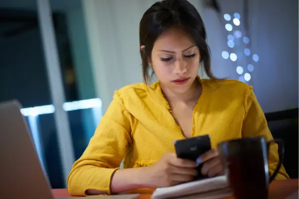 Mulher agendando consulta pelo celular no sofá